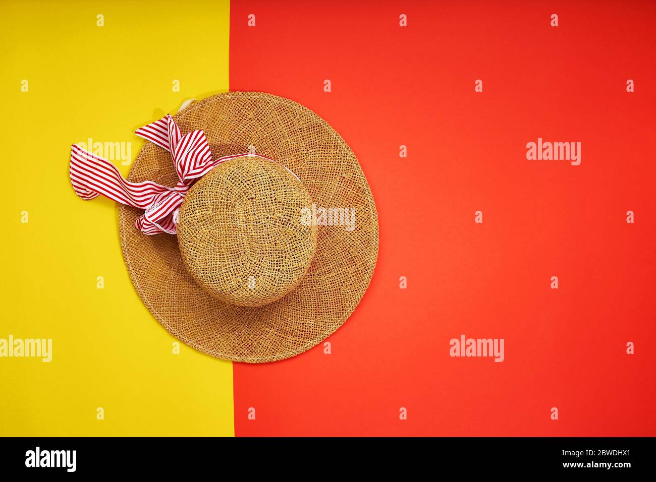 Chapeau de paille isolé sur fond jaune-rouge. Vue de dessus. Concept de vacances et espace de copie. Banque D'Images