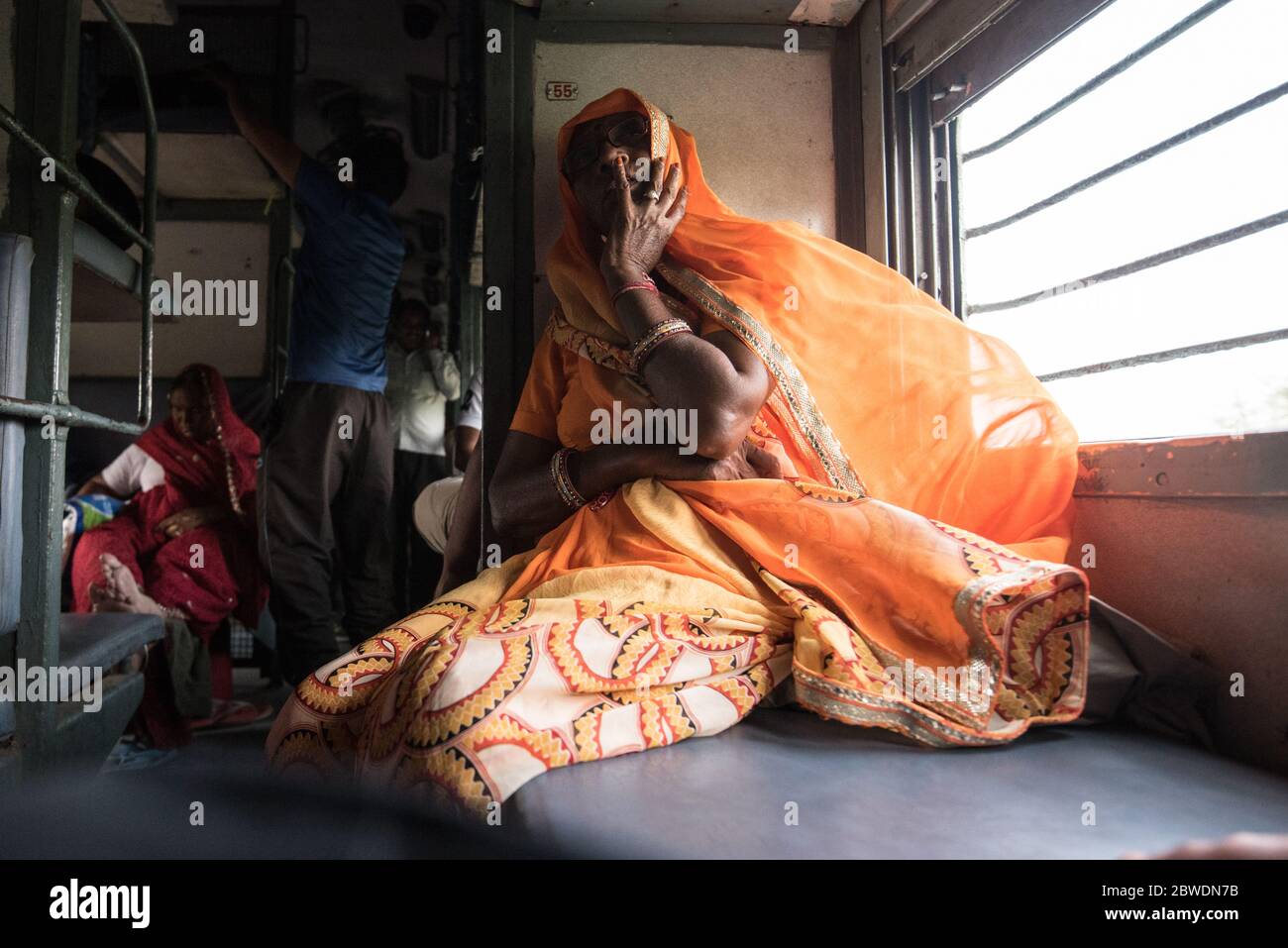 Femme regardant la fenêtre de train mobile, train de deuxième classe. Chemins de fer indiens. Inde. Banque D'Images