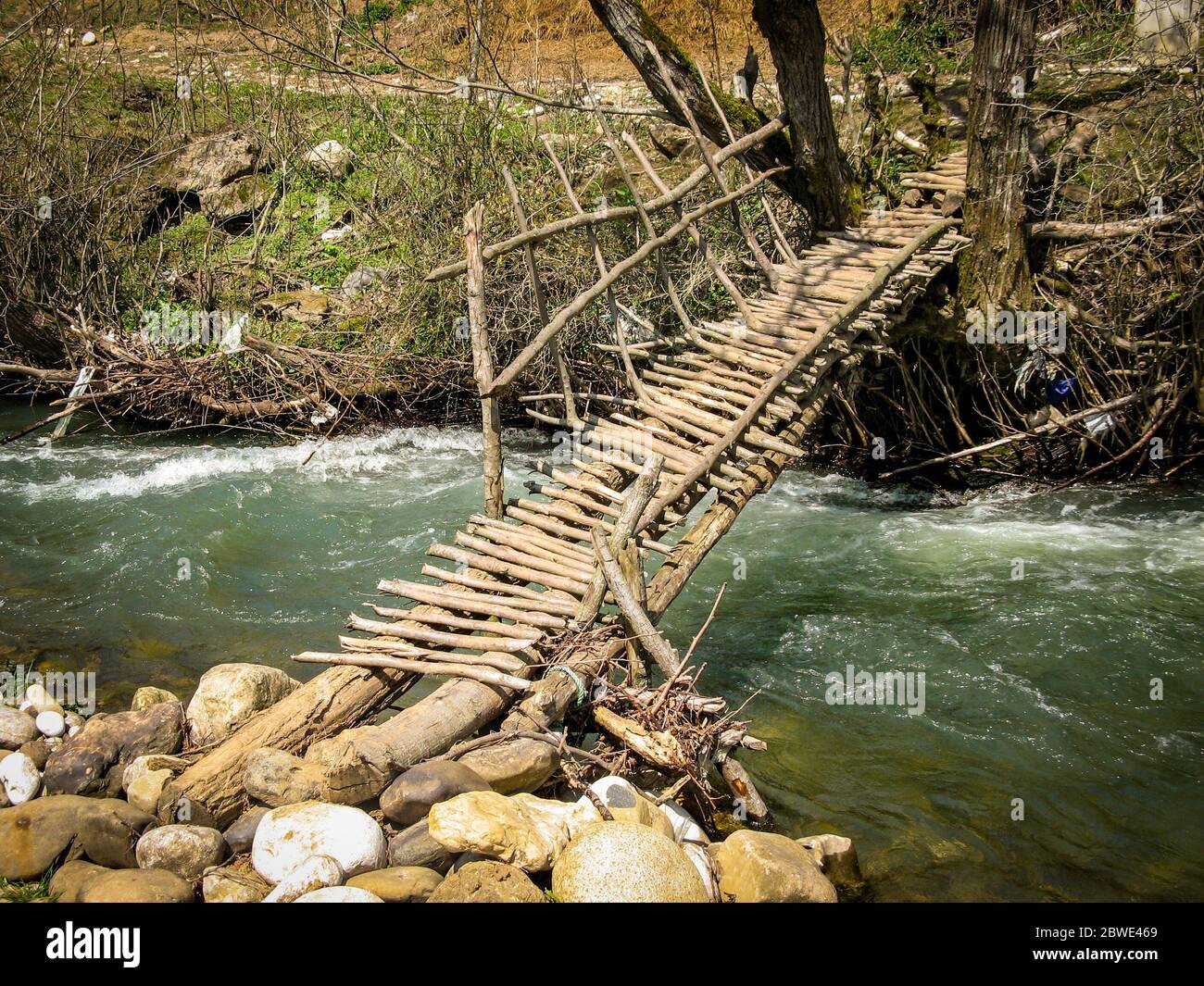 Vieux pont en bois de l'autre côté d'une rivière. Pont en bois avec une rampe sur la rivière eau courante début du printemps. Le vieux pont de parquet en bois Banque D'Images