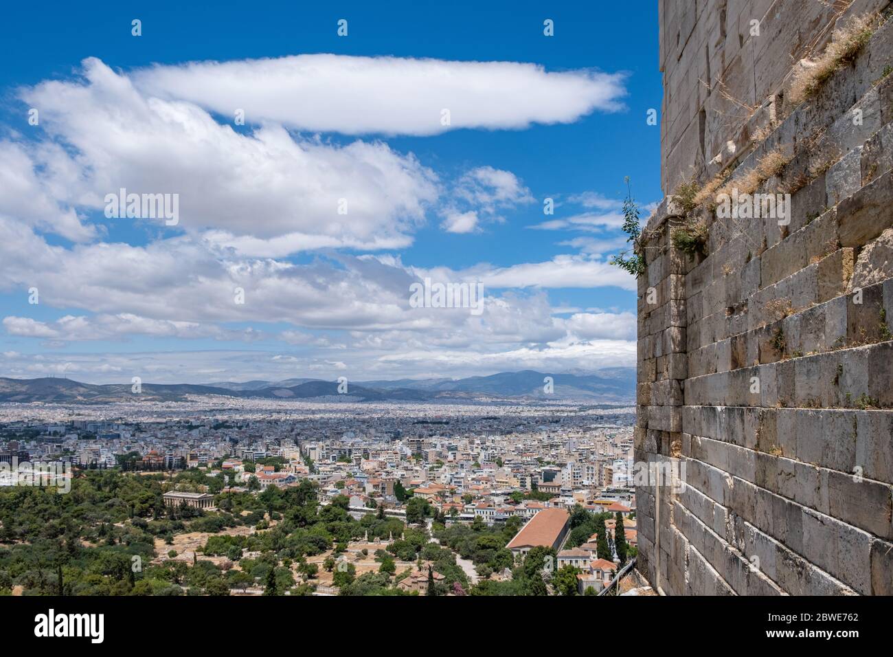 Paysage urbain d'Athènes et temple d'Hephaestus contre ciel bleu nuageux en un jour de printemps. Vue depuis la colline de l'Acropole, partie du mur en pierre de propylaea. Attica, Grèce Banque D'Images