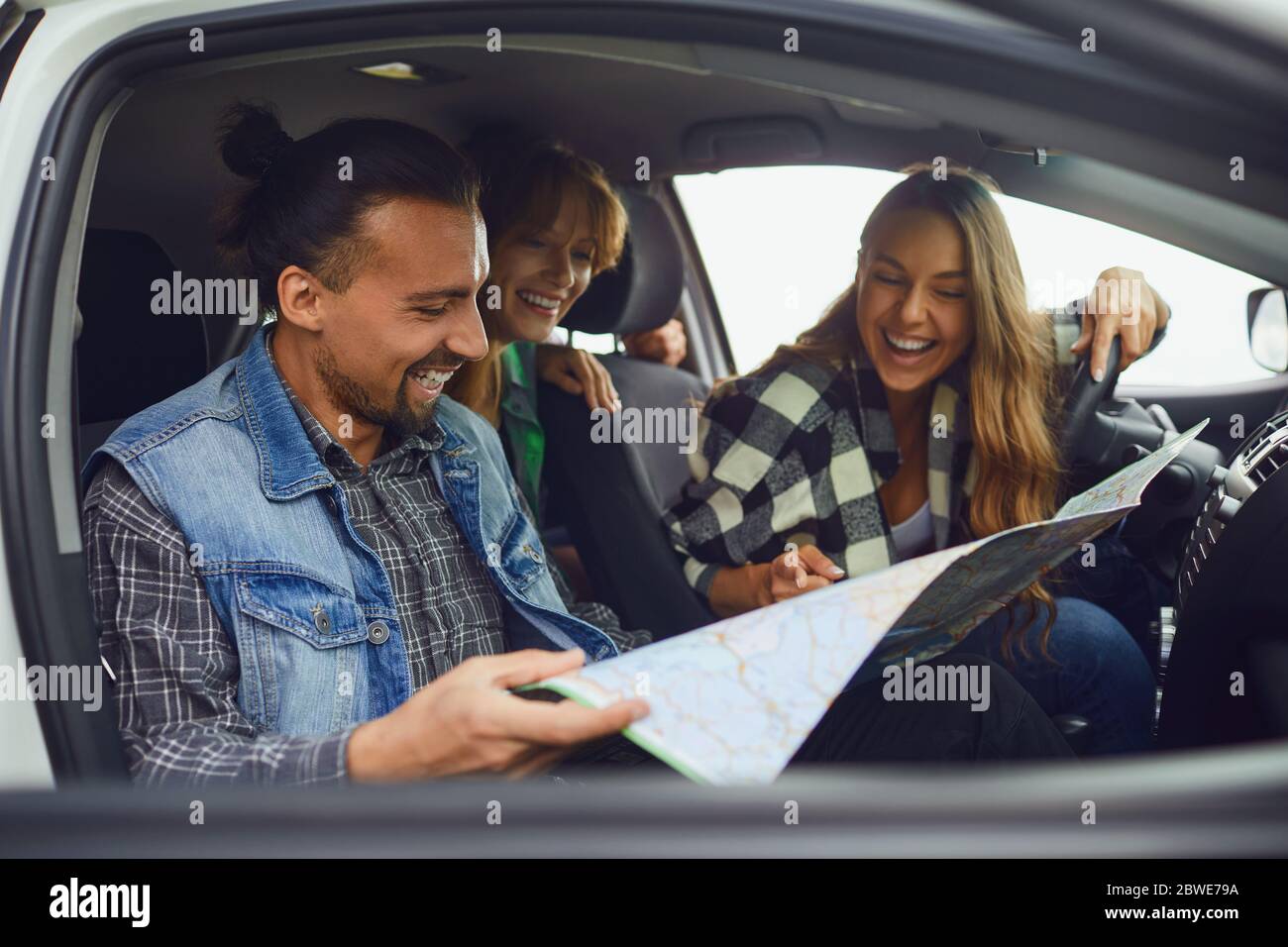 Un groupe d'amis choisissez l'itinéraire sur la carte dans la voiture. Banque D'Images