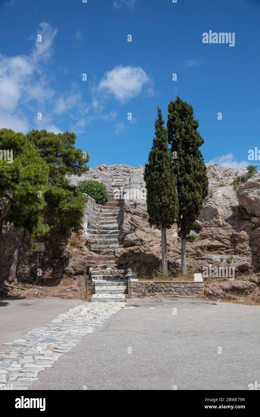 Athènes, Grèce. Escalier en pierre à la colline d'Areopagus, cyprès grec, ciel bleu dans un jour ensoleillé de printemps, photo verticale Banque D'Images