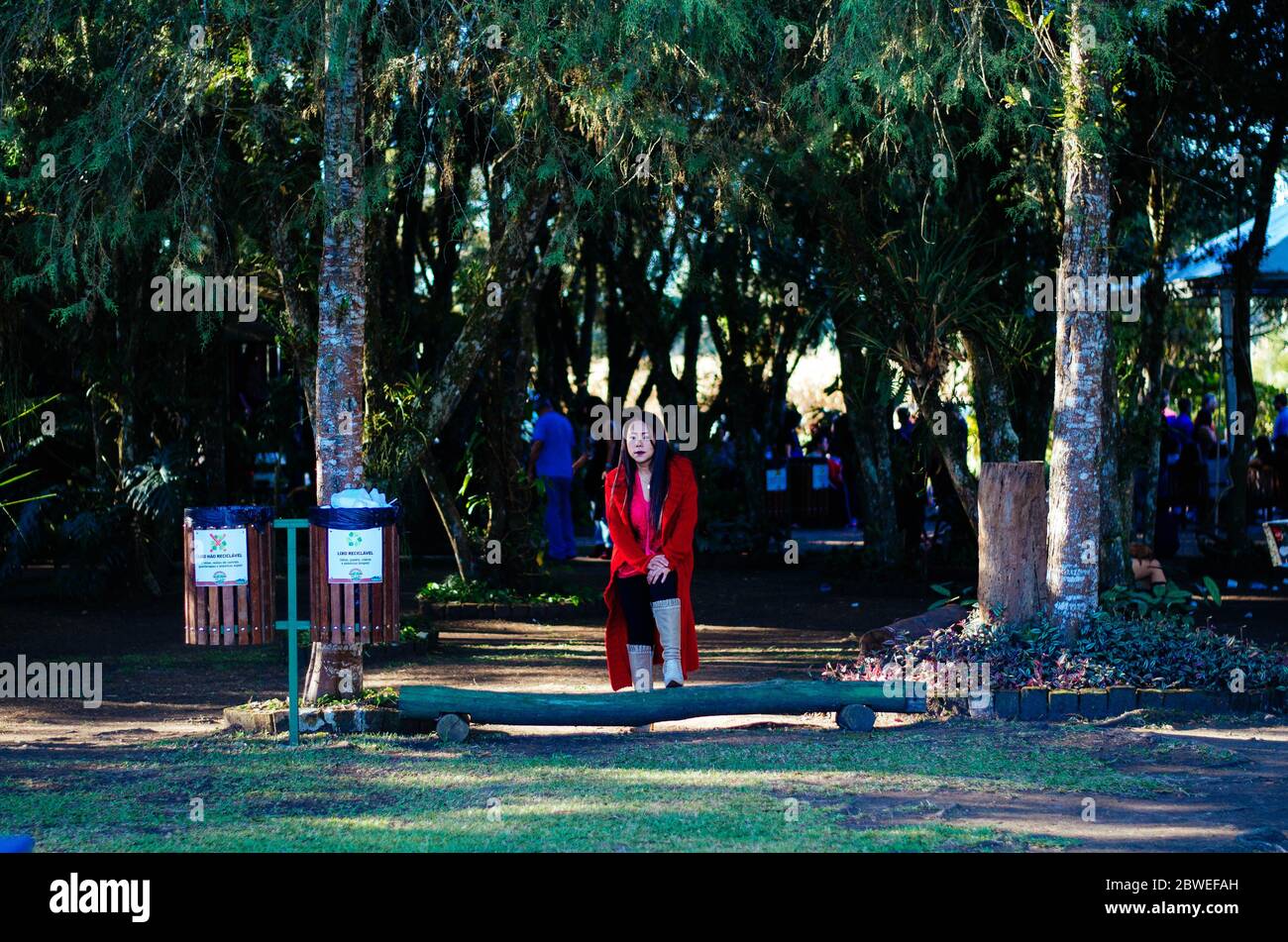 Une femme mature dans ses années 50 utilisant des vêtements élégants, des combinaisons rouges et des bottes en cuir beige posant devant une zone ouverte dans le parc. Banque D'Images