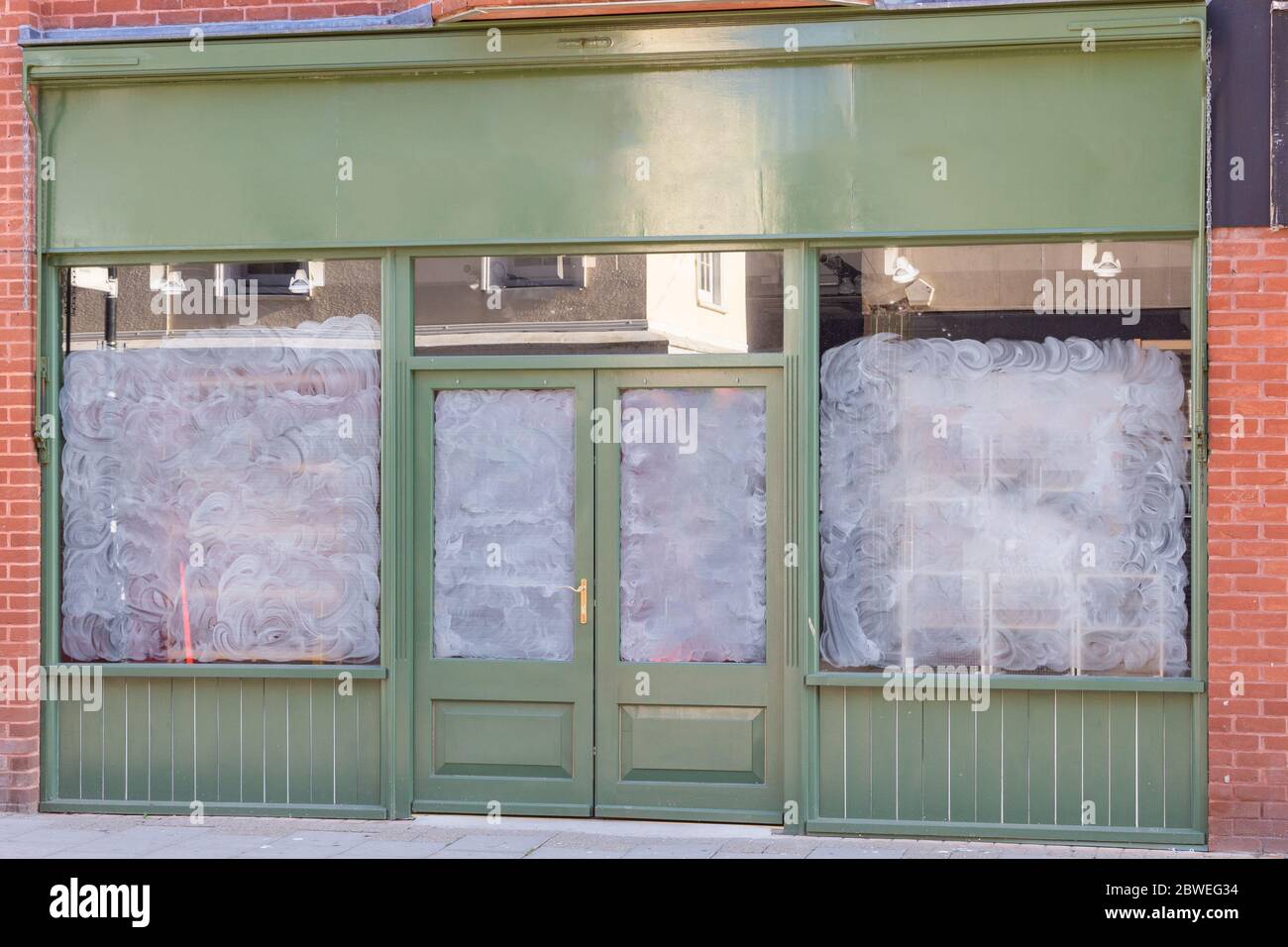 Petite boutique avec façade verte et peinture blanche couvrant les portes et les fenêtres. Banque D'Images