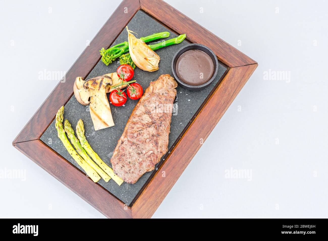 Gros plan sur un médaillon de filet juteux rôti rare. Steak de bœuf gastronomique avec légumes et sauce, assiette en pierre de luxe en bois, repas luxueux Banque D'Images