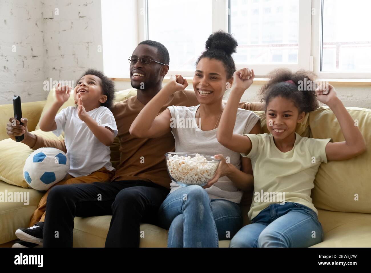 Les amateurs de football familial africains regardant un match assis sur un canapé à l'intérieur Banque D'Images