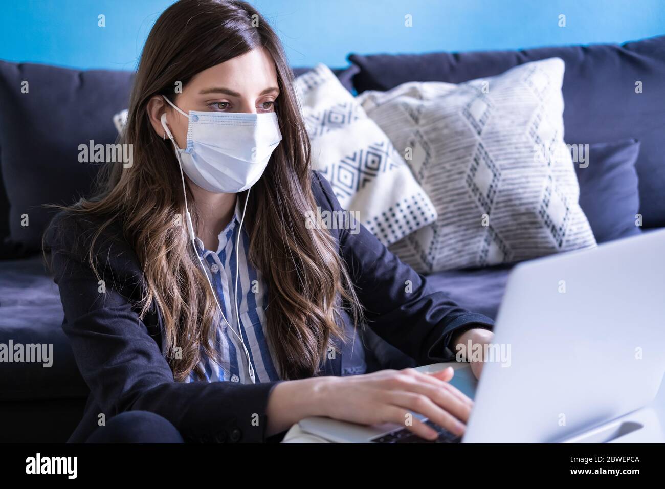 Jeune femme avec masque médical travaillant à la maison. Femme d'affaires faisant bureau à domicile pour la situation de coronavirus. Covid-19 Banque D'Images
