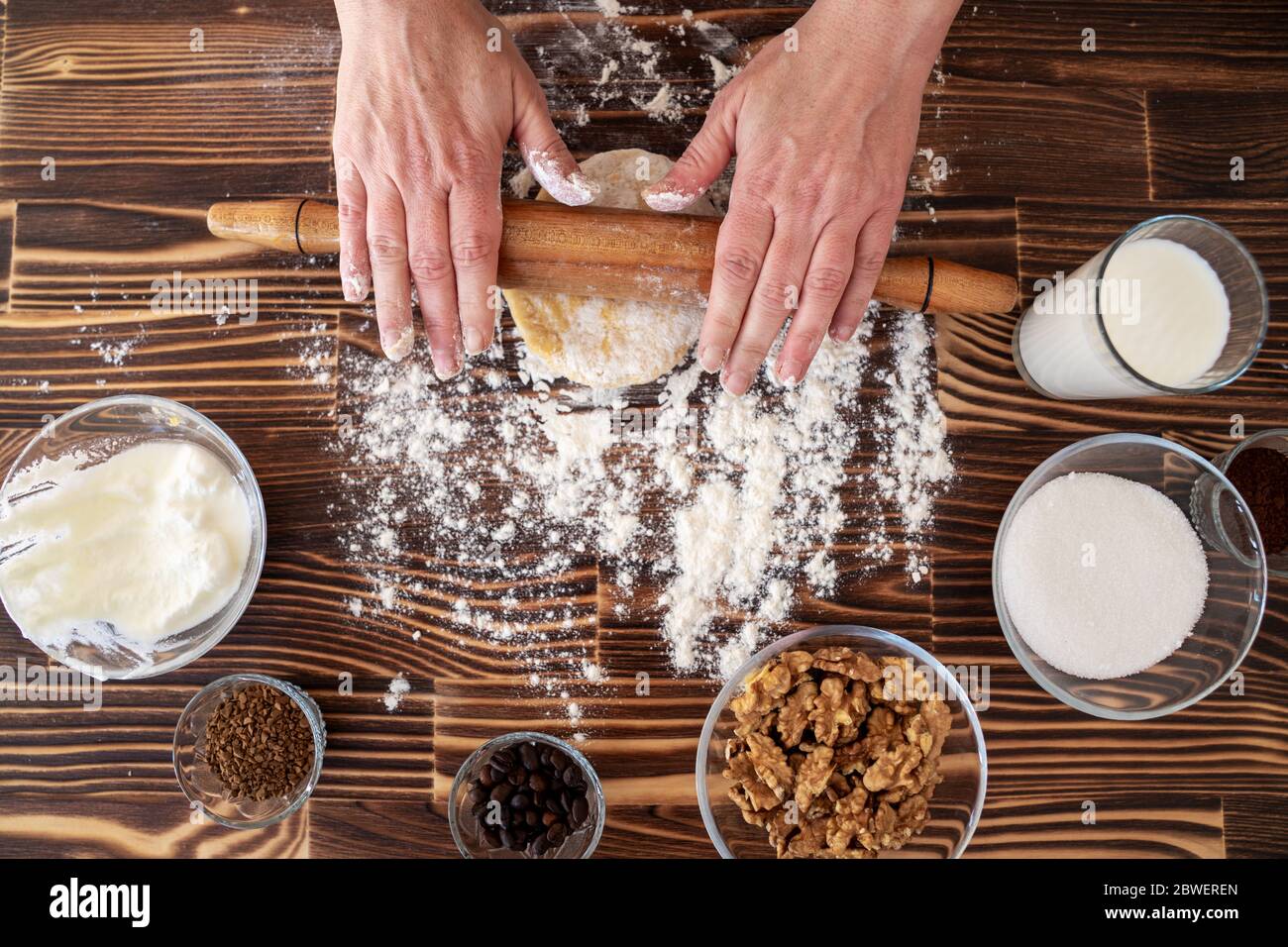 Femme est rouleau à pâtisserie sur la pâte en cuisine, recettes ingrédients pâte et rouleau à pâtisserie sur la table ci-dessus de bois vintage Banque D'Images