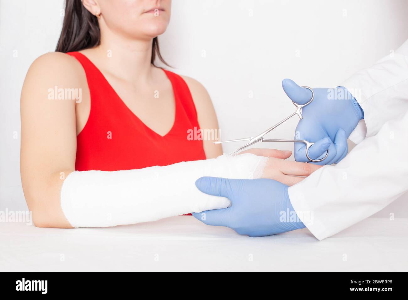 Le médecin traumatologue enlève le bandage de fixation pour une fille qui a une déchirure et une entorse sur son bras, médical, ciseaux chirurgicaux Banque D'Images