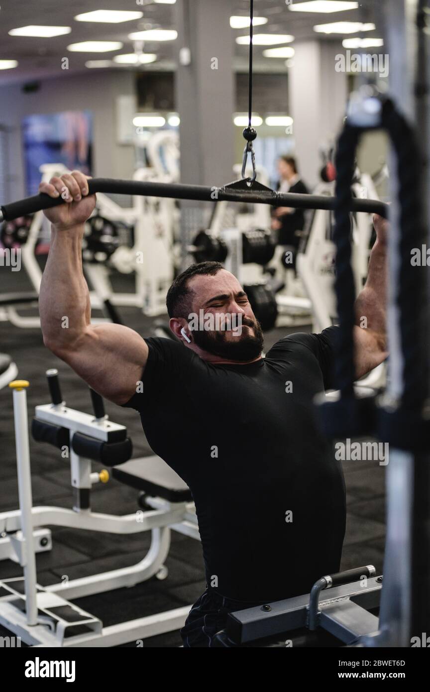 entraînement stress de jeune barbu pendant l'entraînement intensif dans le club de sport gym avec grimace de douleur sur son visage Banque D'Images