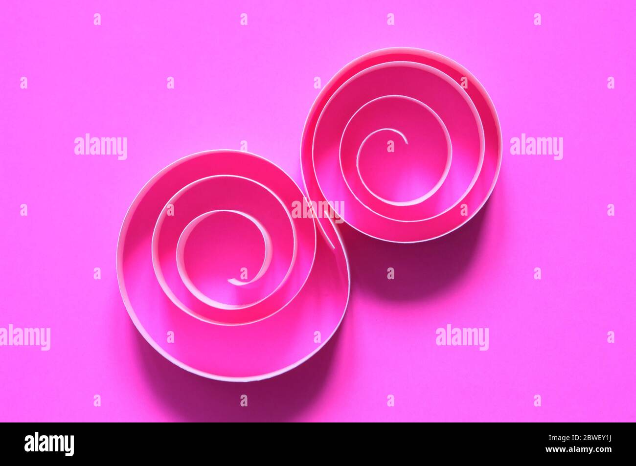 Composition abstraite en spirales de papier sur fond rose Banque D'Images