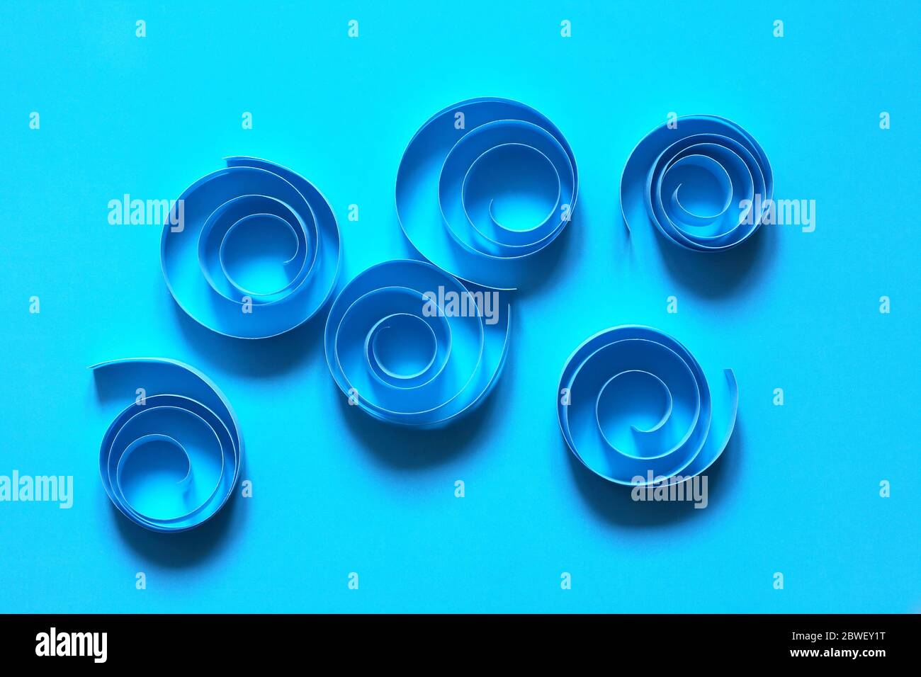 Composition abstraite en spirales en papier sur fond bleu Banque D'Images
