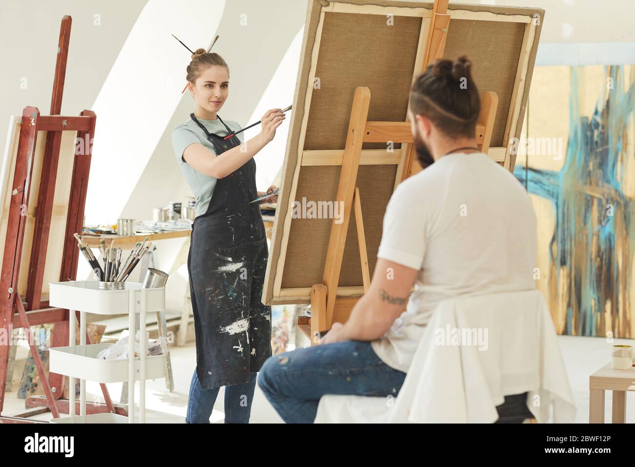 Portrait d'une jeune artiste femme peignant portrait d'un homme en studio, espace de copie Banque D'Images