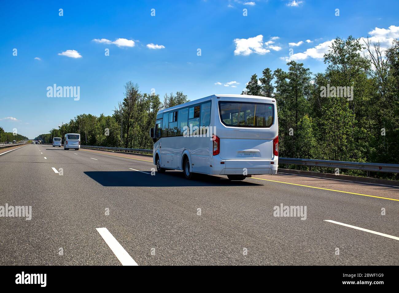 trois nouveaux minibus blancs se trouvent dans un convoi le long de l'autoroute par une journée ensoleillée en été. vue rapprochée, vue arrière Banque D'Images