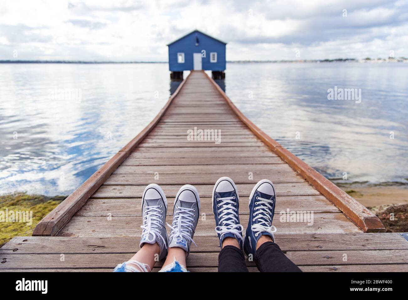 Perth, novembre 2019 : couple touristique portant des baskets profitant de la vue sur la maison de bateau bleue - le hangar de bateau Crawley Edge situé sur la rivière Swan à Perth. Banque D'Images