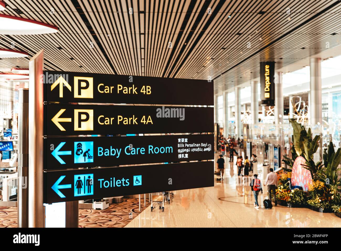 Singapour, aéroport de Changi, novembre 19 : intérieur moderne du terminal 4 rempli de touristes. Panneau indiquant les directions vers le parking, les toilettes et les services de garde d'enfants Banque D'Images