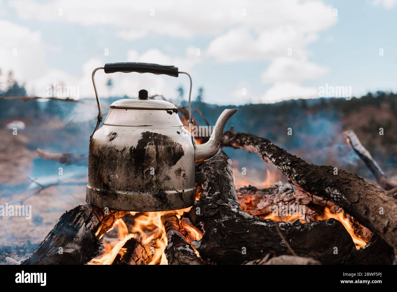 Eau bouillante lors d'un voyage en camping avec feu dans les montagnes,  cuisine sur feu avec bois de chauffage. Bouilloire sur feu. Pique-nique  Photo Stock - Alamy