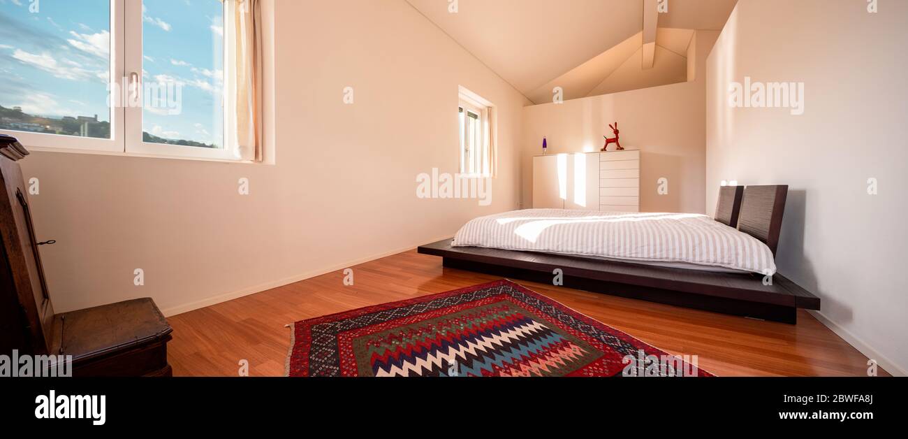 Intérieur d'une chambre minimale, avec un seul lit et un faisceau de lumière entrant. Le sol est en bois et le lit est bas, de style japonais. Banque D'Images