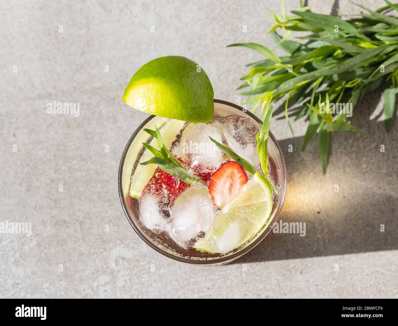 cocktail rafraîchissant d'été, limonade avec glace, fraises, citron vert et estragon dans un verre Banque D'Images