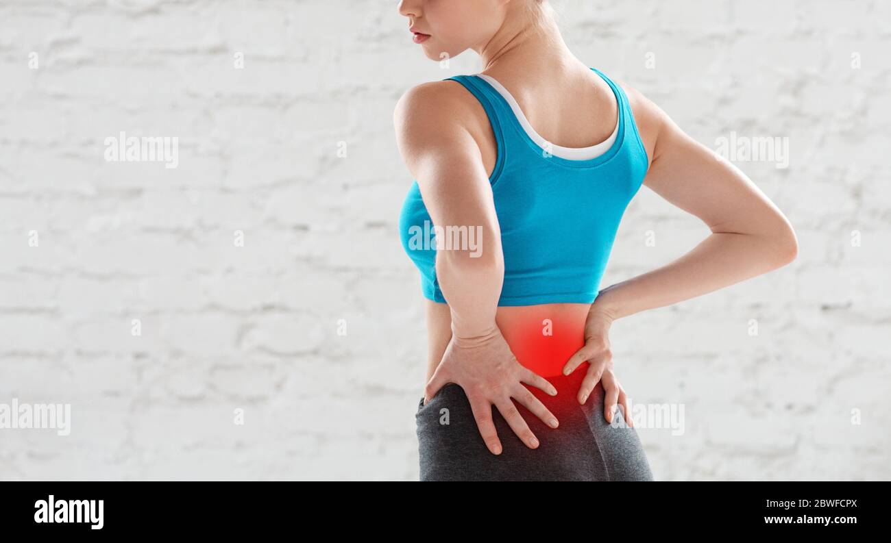 Vue rognée d'une jeune femme qui ressent des douleurs dans le bas du dos après un entraînement à la salle de gym, espace de copie Banque D'Images