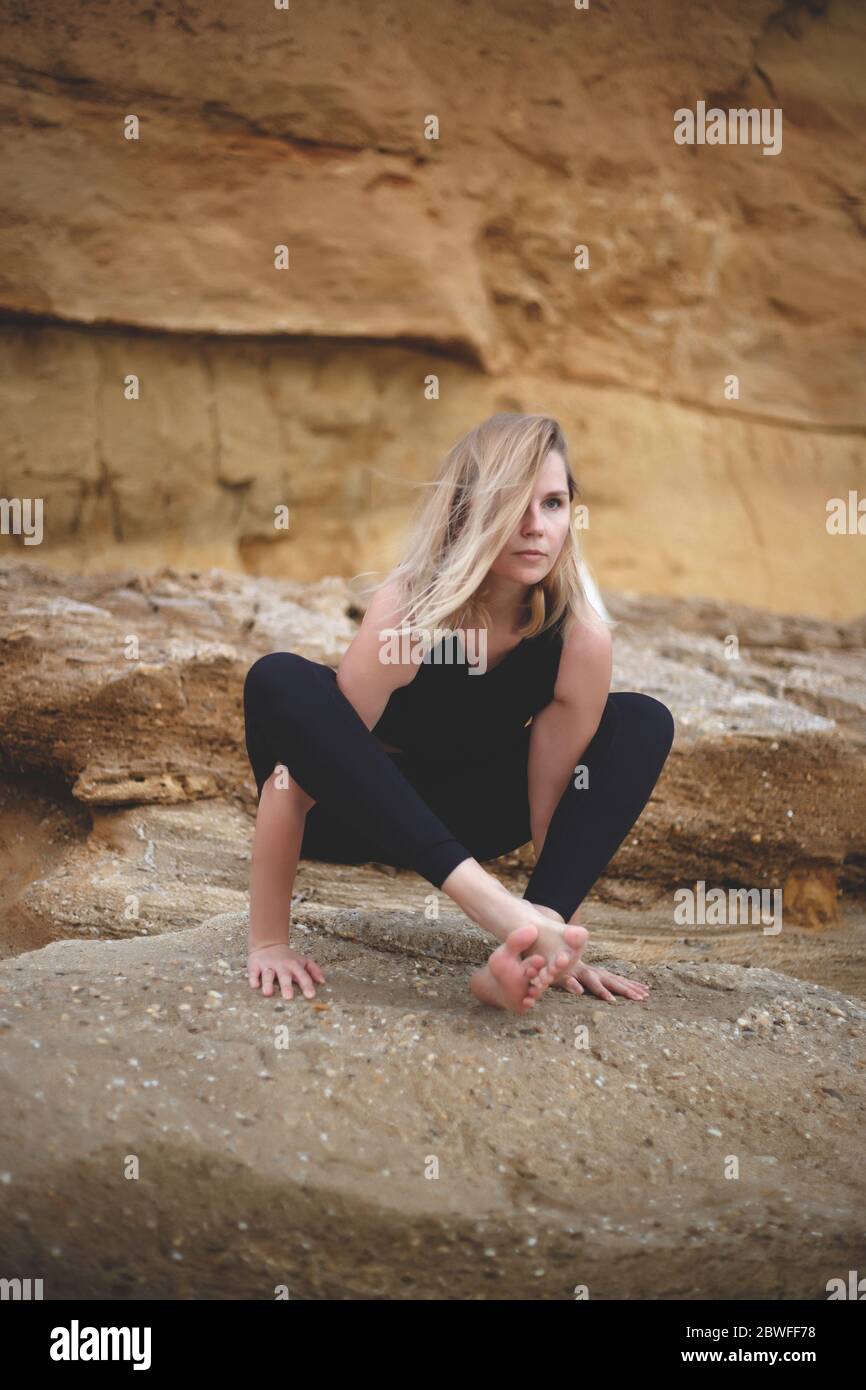 une femme pratique le yoga en bord de mer sur fond de falaise Banque D'Images