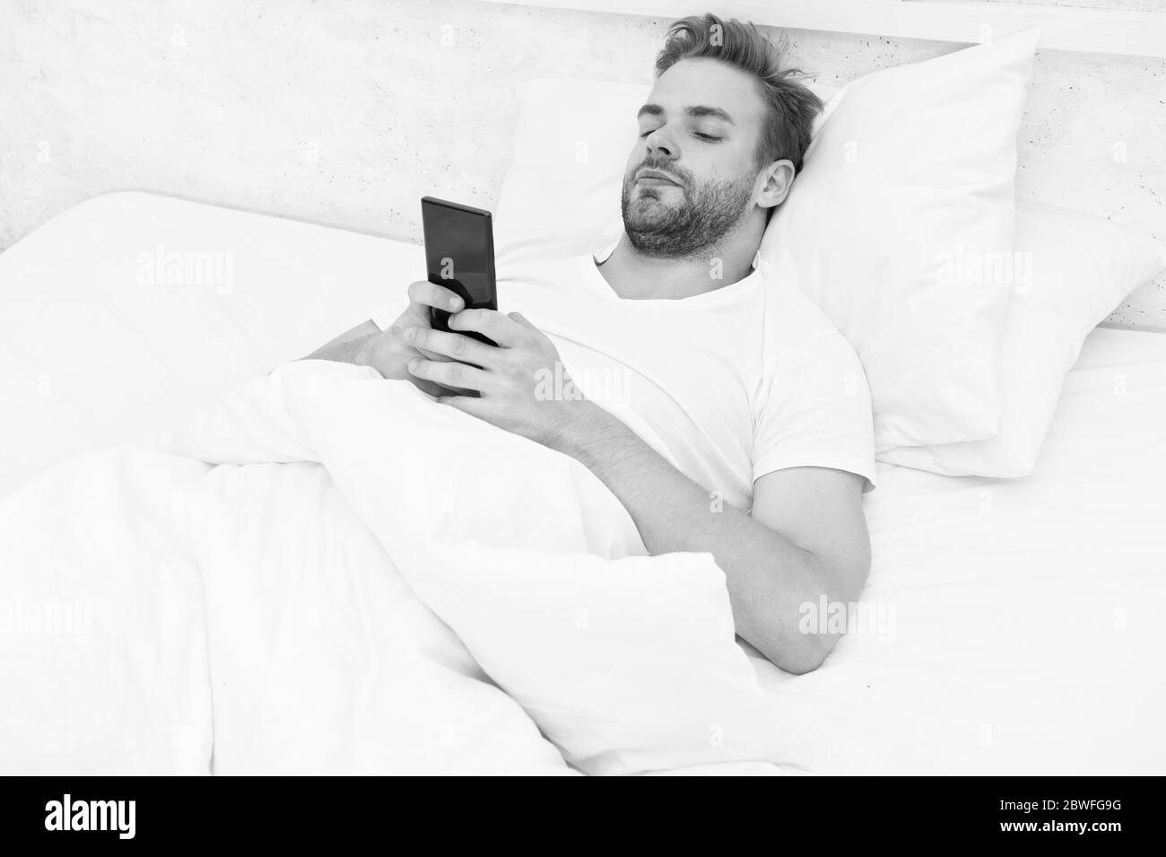 le matin vibes. tout le monde au téléphone. il est blogging. flirting et envoi de message texte. internet addiction et mobile abus concept. homme dans le lit chat. l'homme utilise smartphone dès le début de la matinée. Banque D'Images