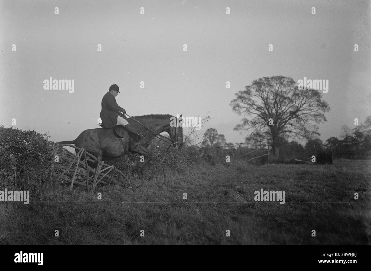 La brigade de la maison Draghounds se rencontrer . La brigade des ménages Draghounds s'est réunie à Stoke Green House , Stoke Poges , la résidence de Lady Currie . Ici un suiveur de gentleman peut être vu prendre une clôture . 10 novembre 1923 Banque D'Images