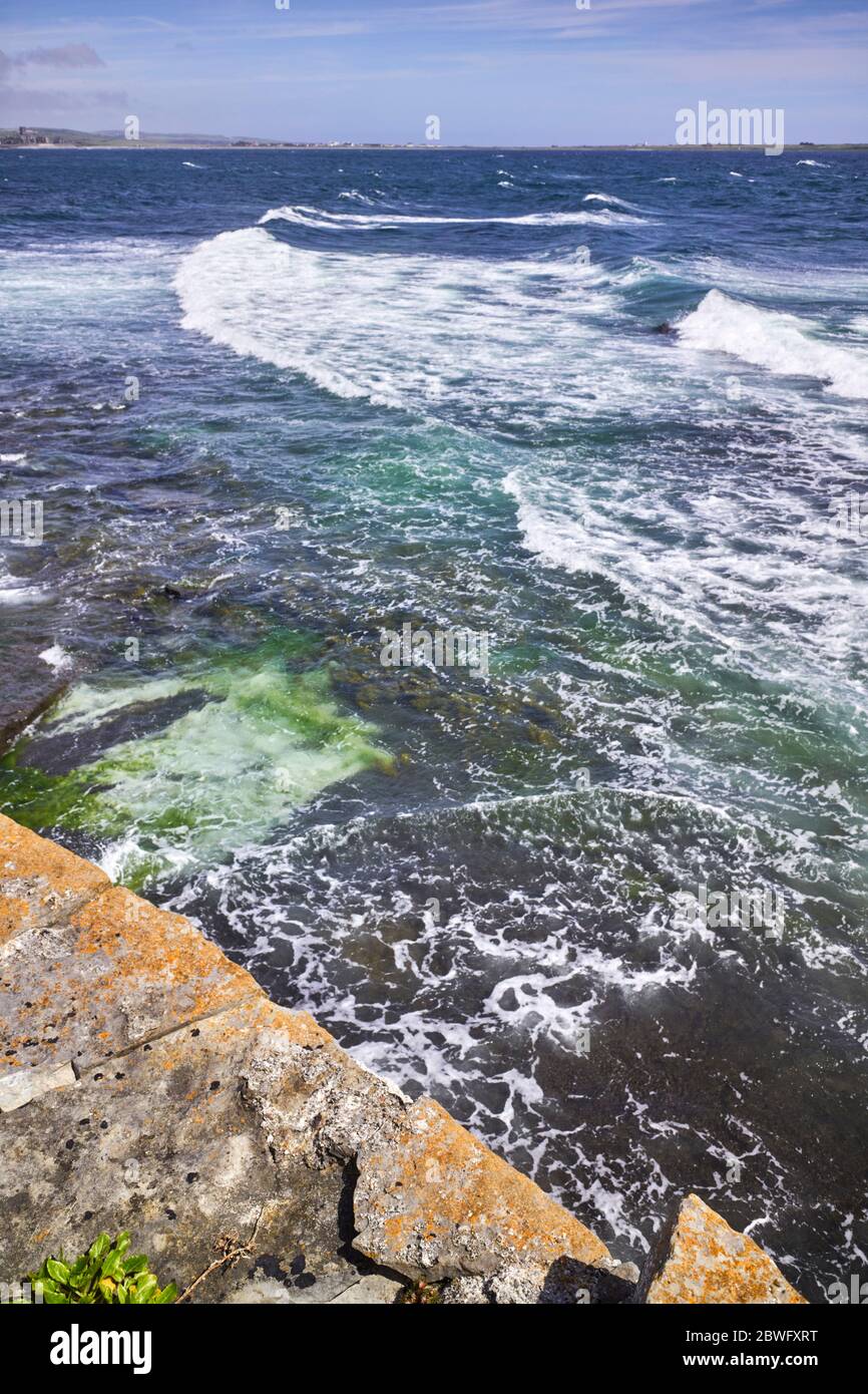 Vagues entrant dans la baie de Castletown par une journée venteuse avec lichen recouvert de calcaire en premier plan Banque D'Images