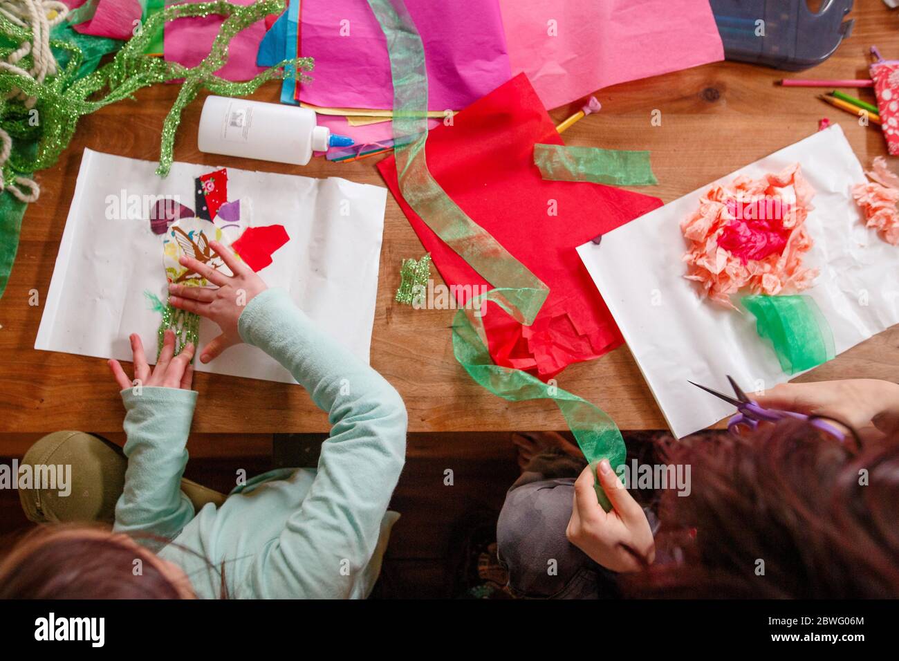Vue de haut en bas de deux enfants faisant de l'art et de l'artisanat à une table en bois Banque D'Images