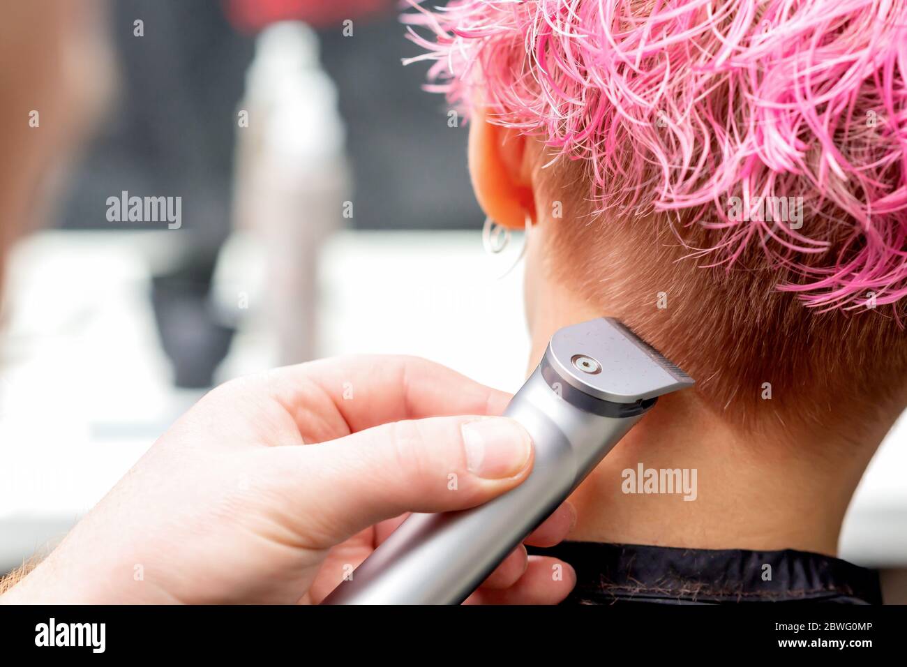 Vue arrière la main de coiffure est de raser les cheveux roses de la femme  avec la tondeuse électrique dans le salon de coiffure, gros plan Photo  Stock - Alamy