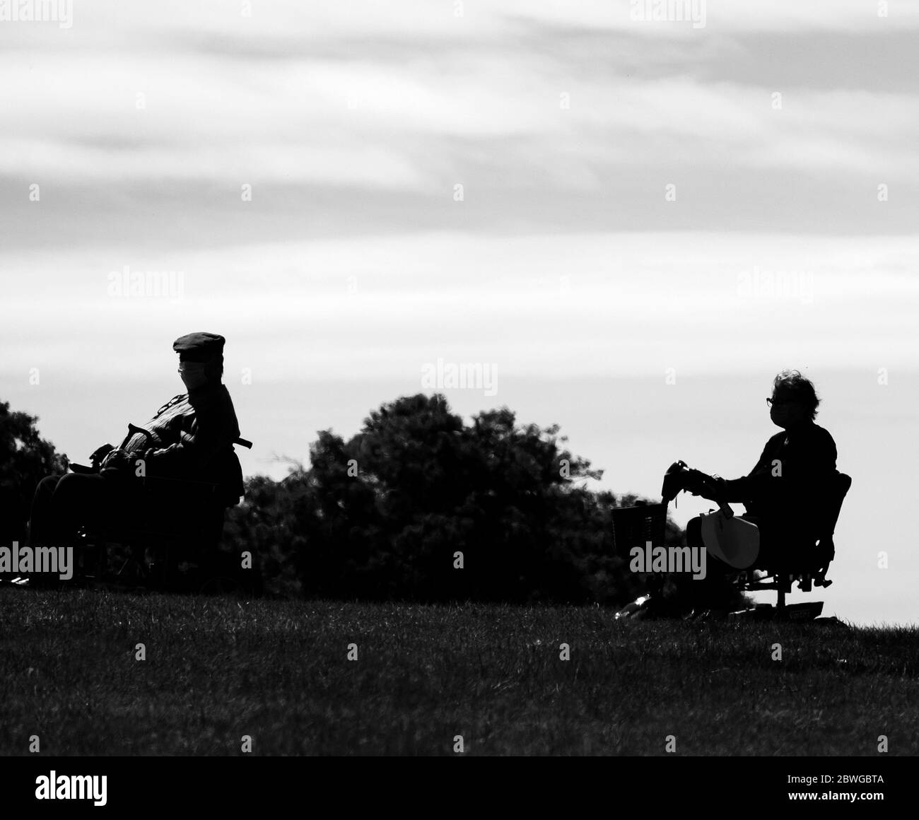 Deux personnes âgées sur des scooters de mobilité observant des distances sociales Banque D'Images