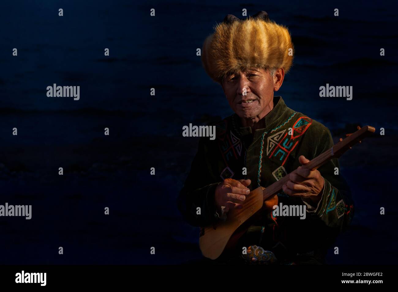 Homme local jouant un instrument de musique kirghize traditionnel connu sous le nom de Komuz, dans le lac Issyk Kul, Kirghizistan Banque D'Images