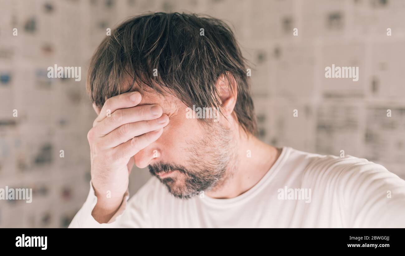 Homme déprimé dans le concept infodemique, homme adulte avec la tête dans les mains pleurant confus Banque D'Images