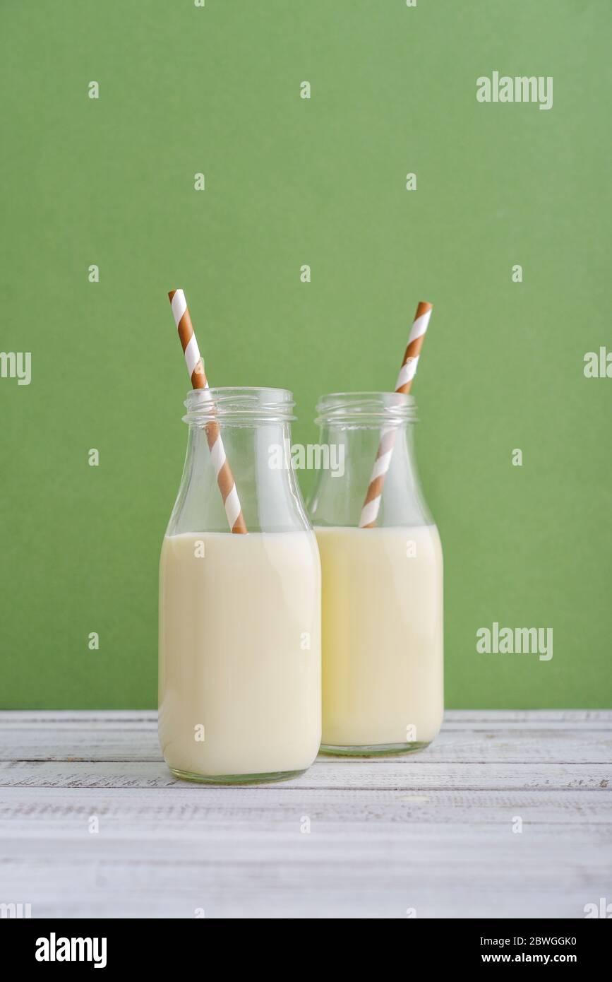 Deux bouteilles de lait et de pailles à boire sur fond vert Banque D'Images