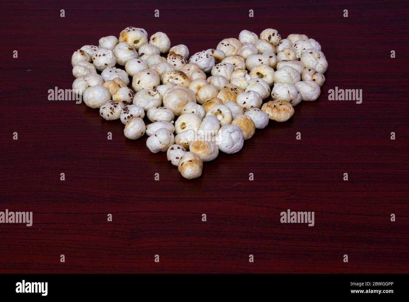 Makhana aussi connu comme graines de lotus sont disposés ou groupés en forme de coeur sur la table en bois brun montre l'avantage pour la santé vers le coeur Banque D'Images