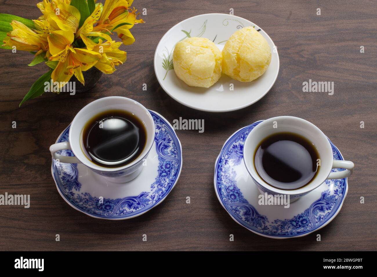 Pain au fromage brésilien et deux tasses de café sur la table en bois sombre. Banque D'Images