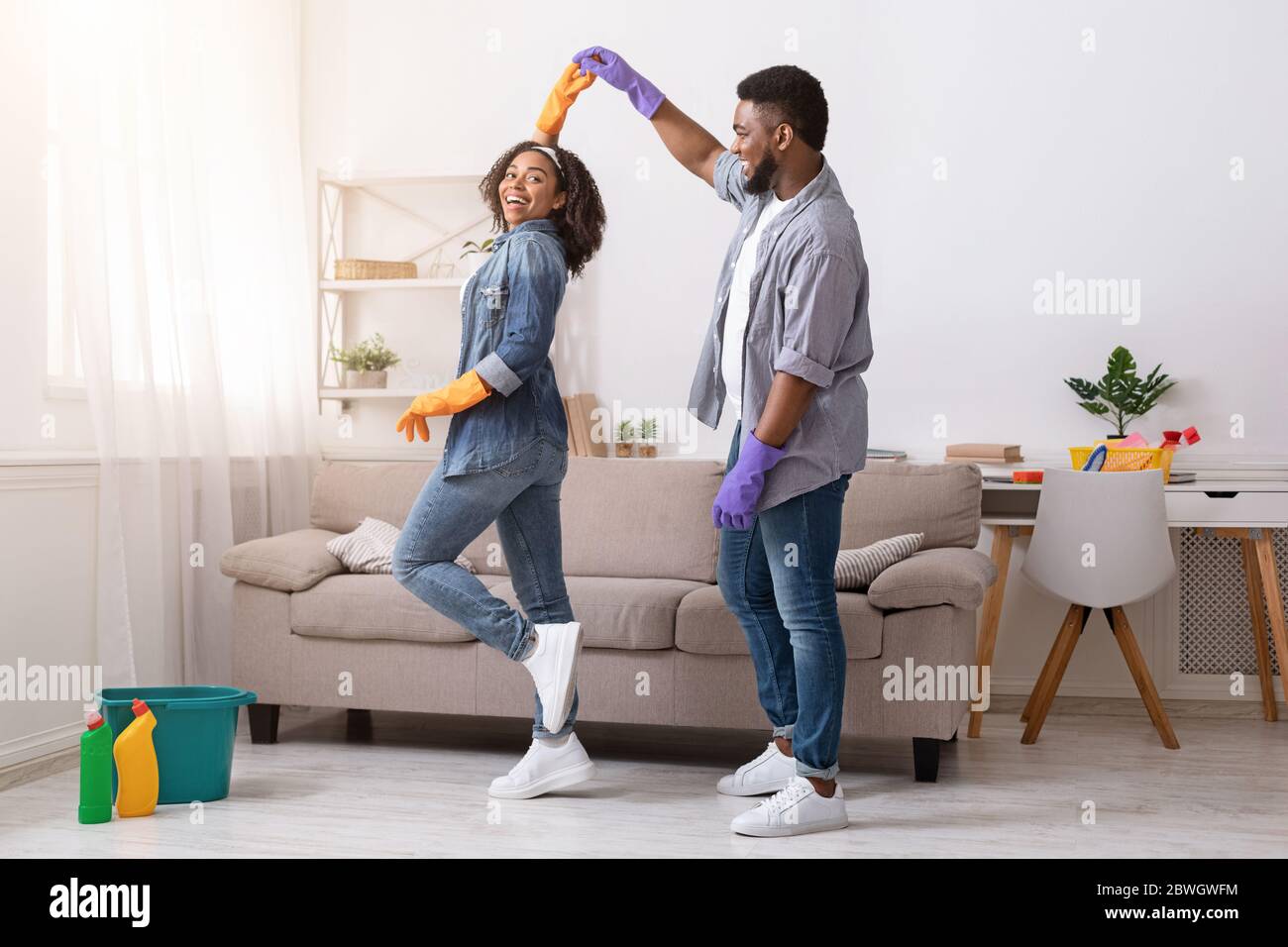 Amoureux couple afro-américain dansant tout en nettoyant à plat ensemble Banque D'Images