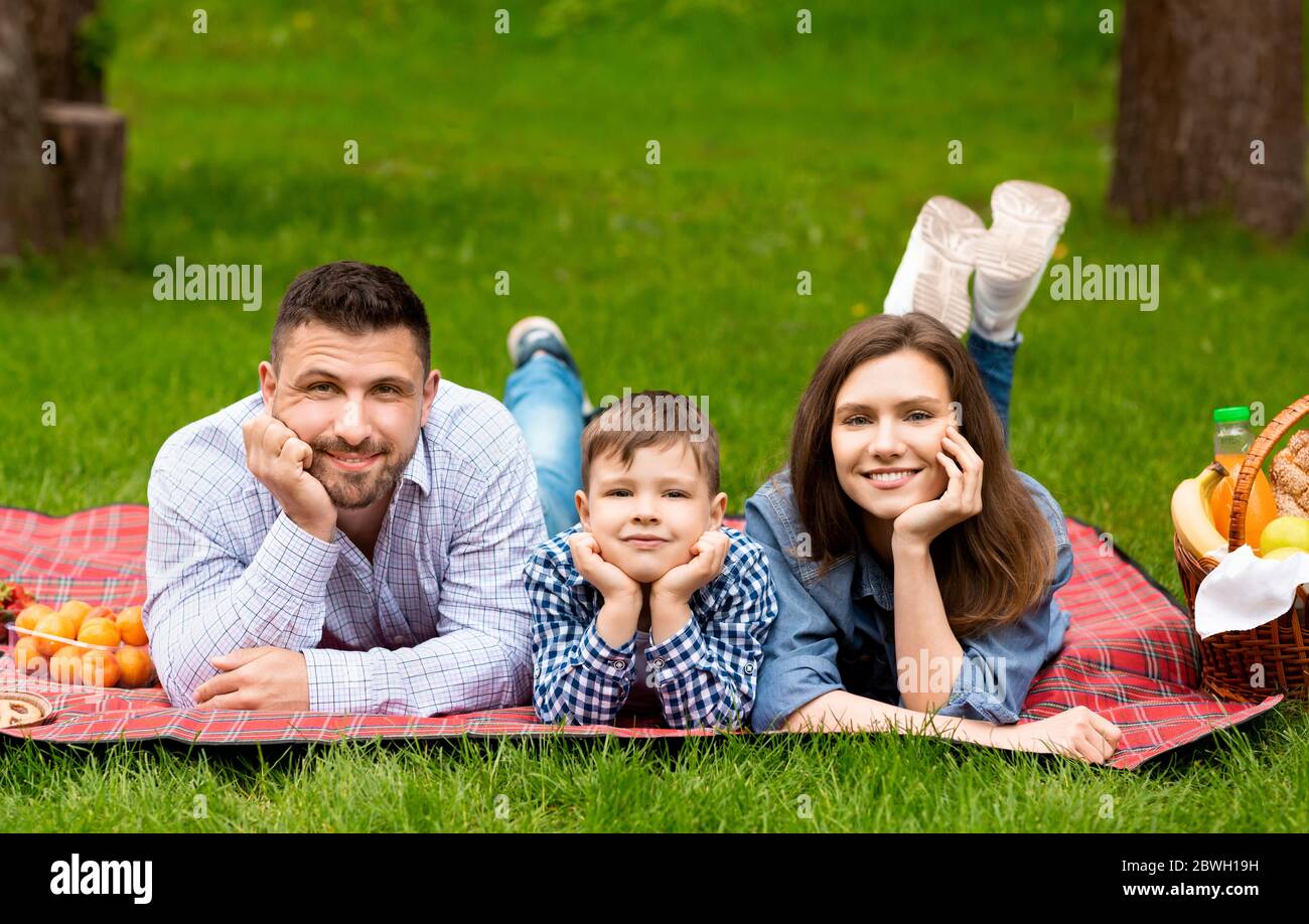 Des moments de détente en famille. Adorable garçon avec parents allongé sur une couverture pendant le pique-nique dans le parc Banque D'Images