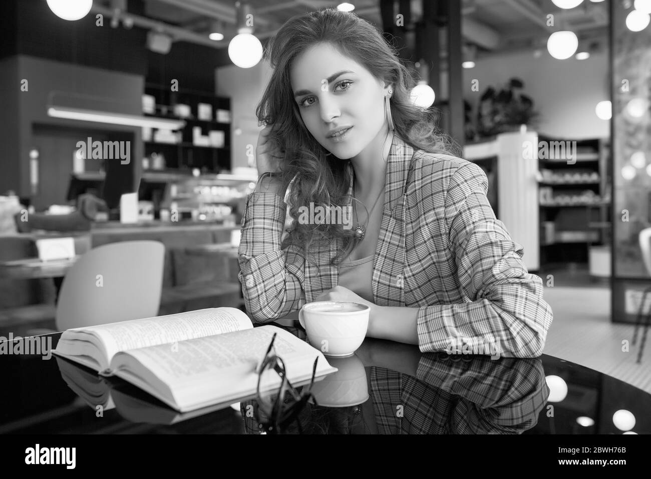 Portrait de jeune belle femme boit le café et livre de lecture dans l'intérieur du café Banque D'Images