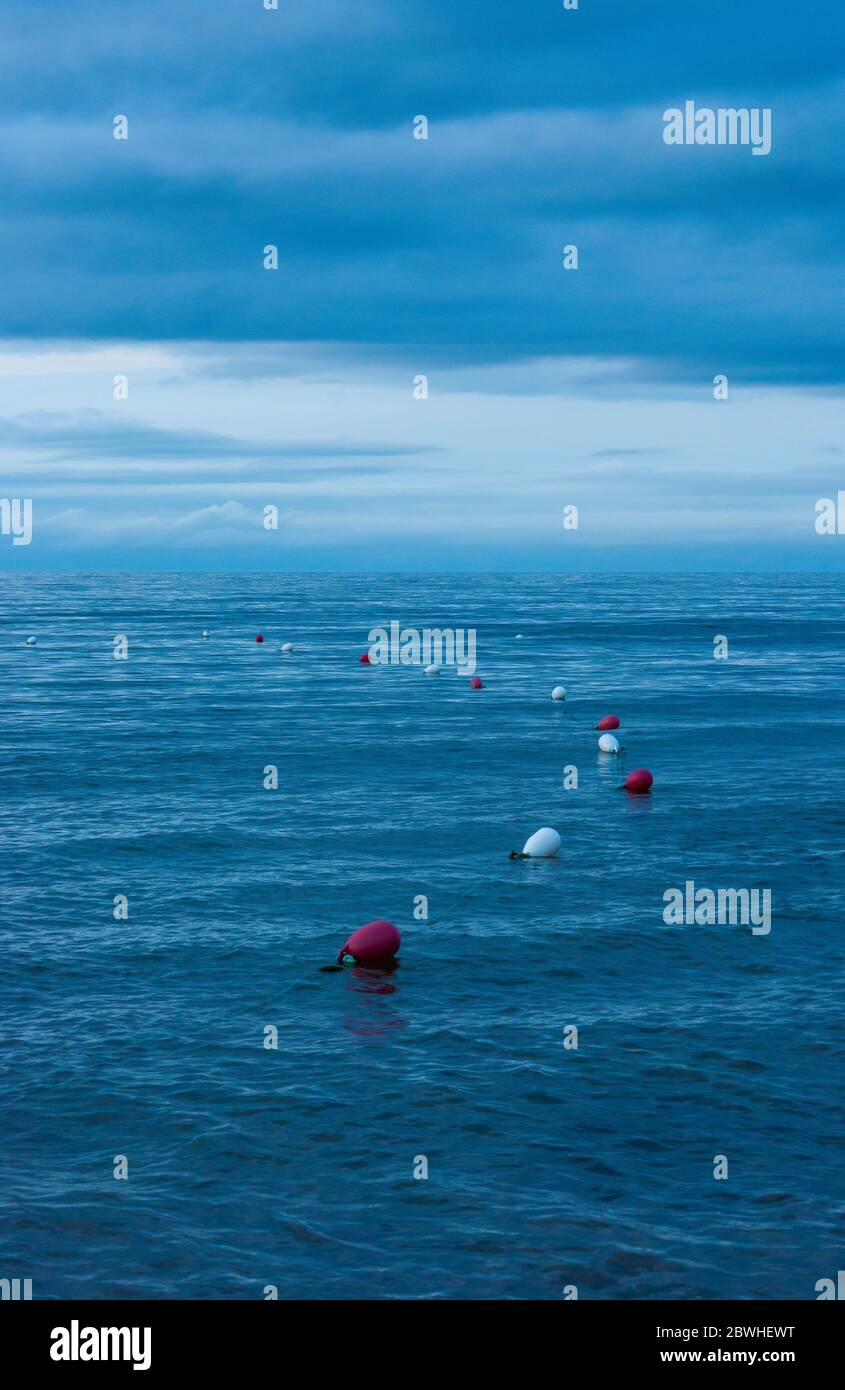 Bouées de natation marquant le périmètre d'une zone de baignade surveillée. Eaux ondulées au crépuscule. Cavendish Beach, parc national du Canada de l'Île-du-Prince-Édouard Banque D'Images