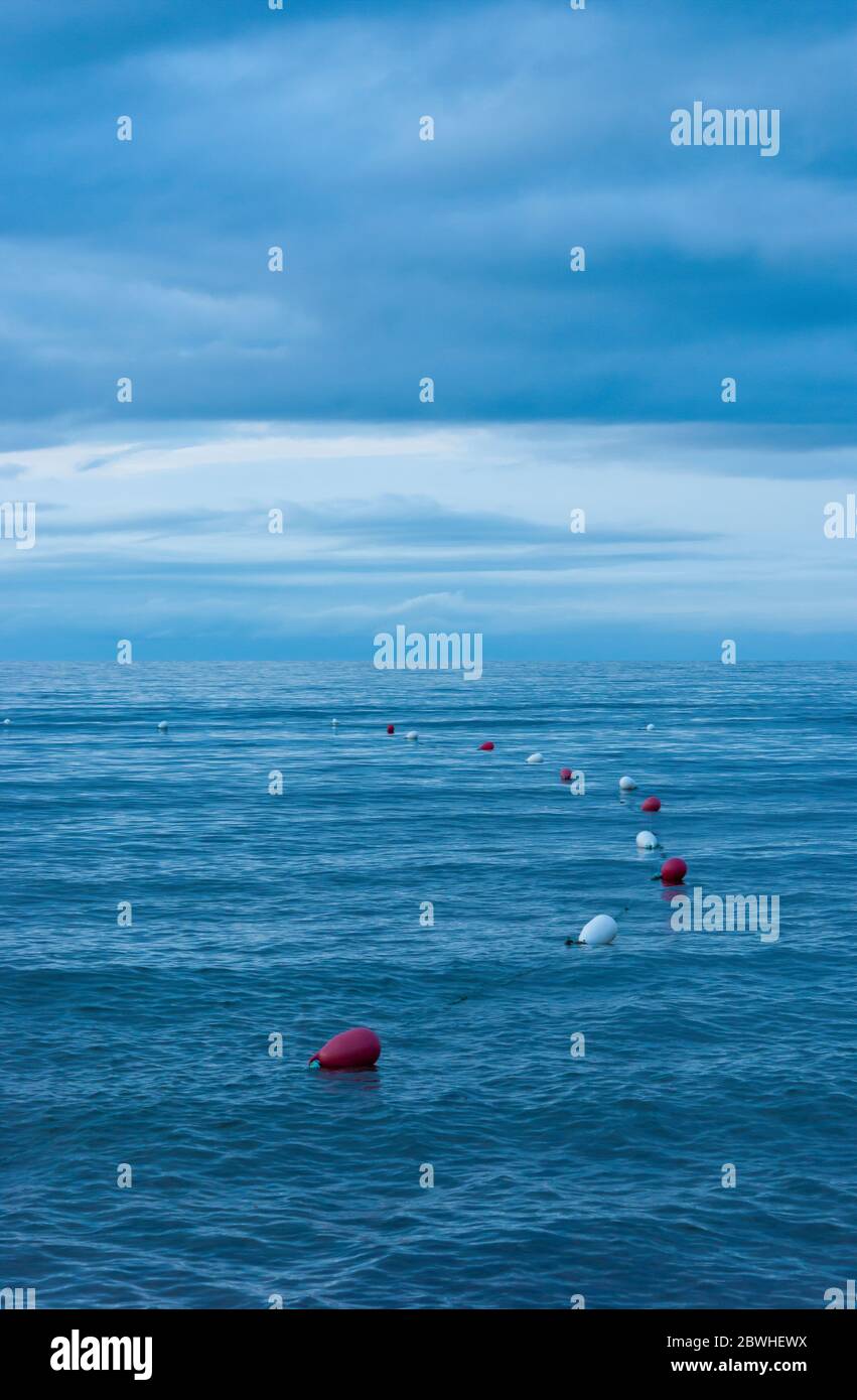 Bouées de natation marquant le périmètre d'une zone de baignade surveillée. Eaux ondulées au crépuscule. Cavendish Beach, parc national du Canada de l'Île-du-Prince-Édouard Banque D'Images
