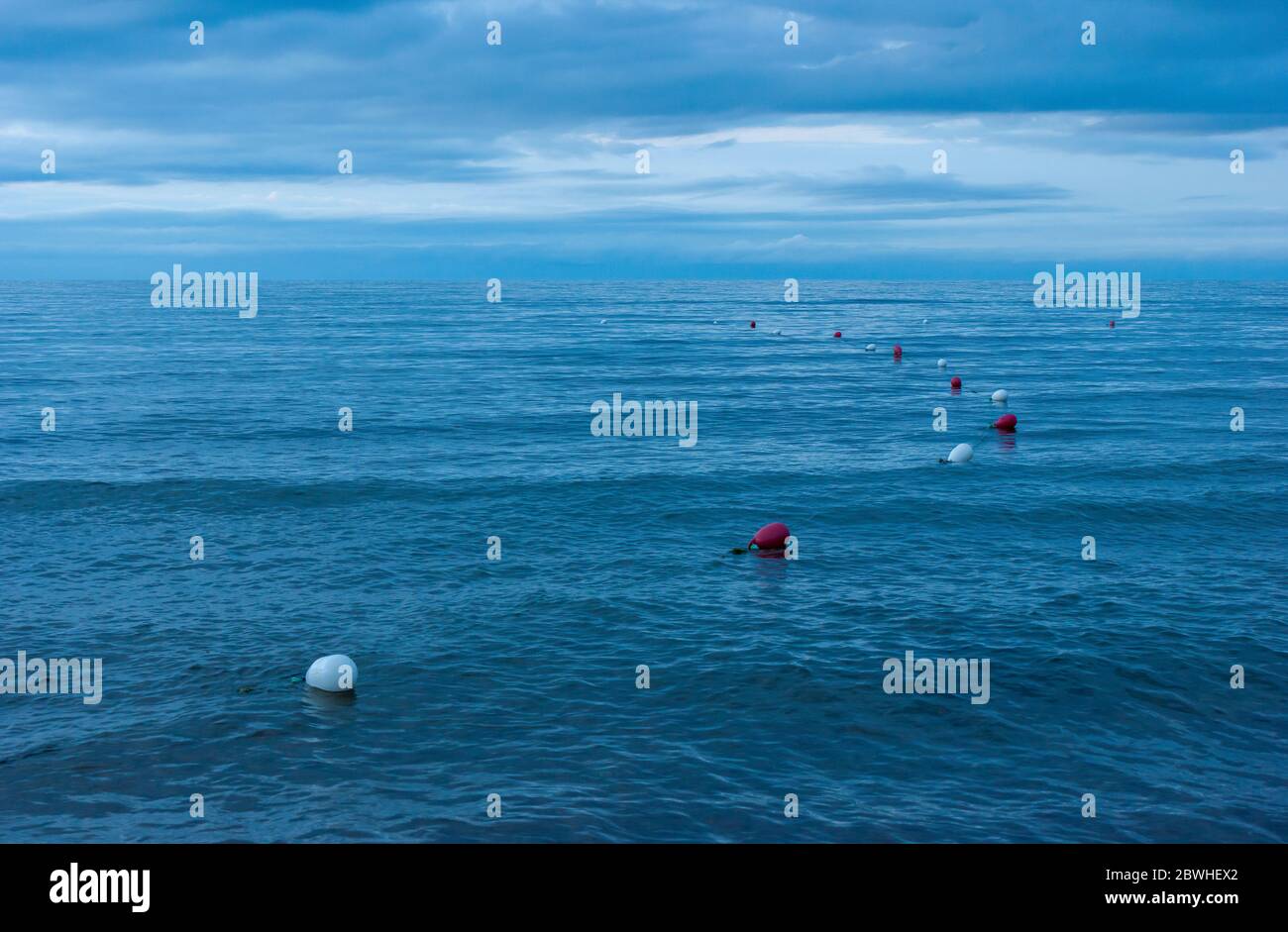 Bouées de natation marquant le périmètre d'une zone de baignade surveillée. Eaux ondulées au crépuscule. Cavendish Beach, parc national du Canada de l'Île-du-Prince-Édouard Banque D'Images