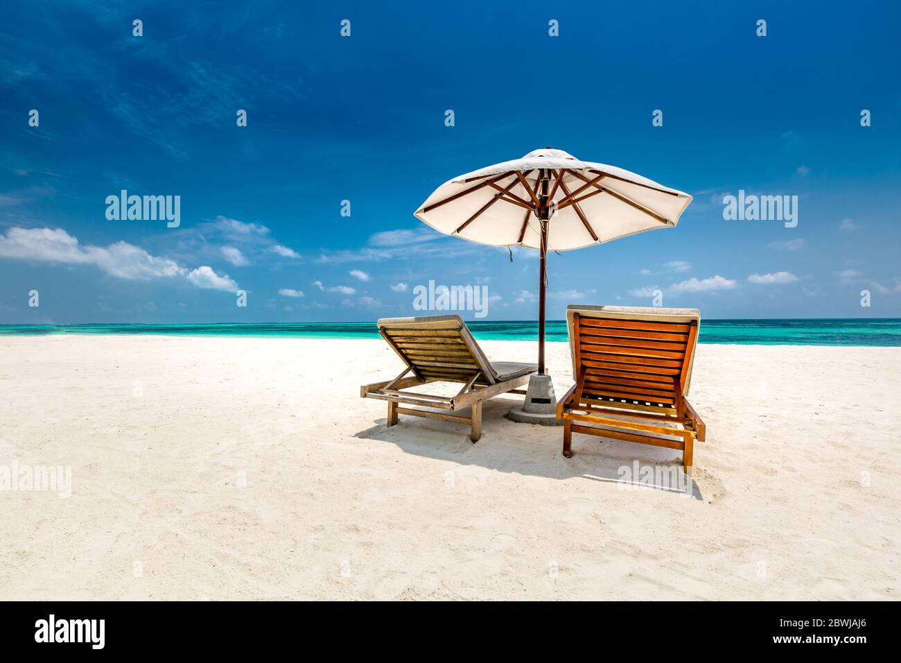 Paysage de plage tropical parfait, sable blanc sur mer bleue et ciel bleu. Paysage de vacances d'été idyllique et exotique. Vacances à la plage, chaises, parasol Banque D'Images