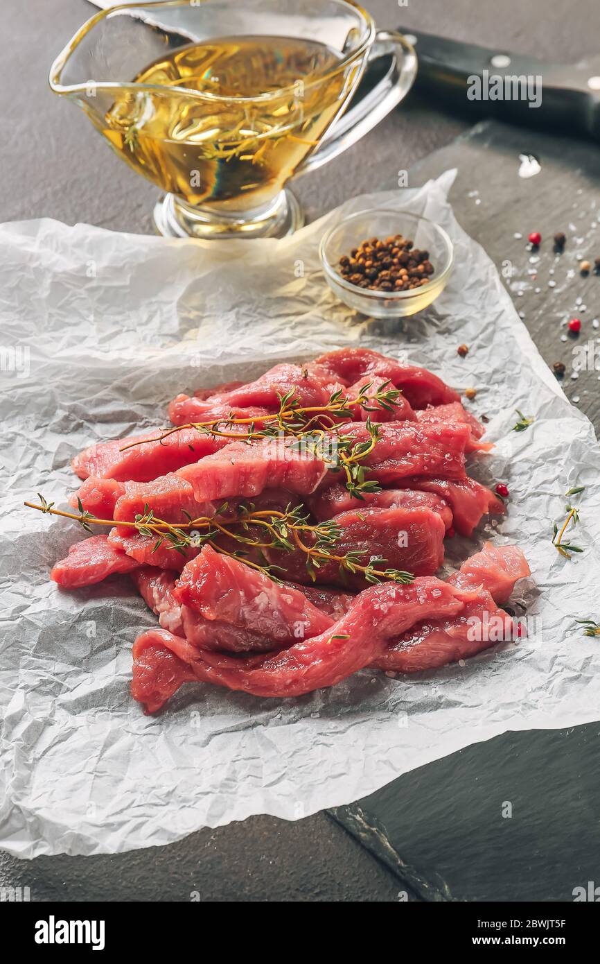Morceaux de viande de bœuf fraîche avec épices et huile sur table Banque D'Images