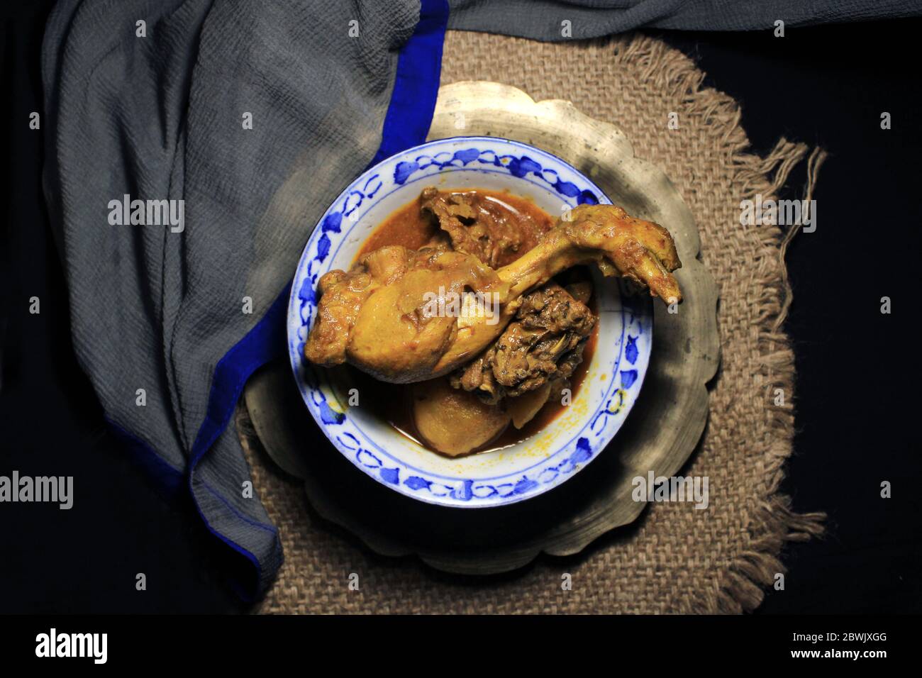 Curry de poulet cuit dans une casserole blanche. Curry de poulet chaud et épicé isolé sur fond noir. Banque D'Images