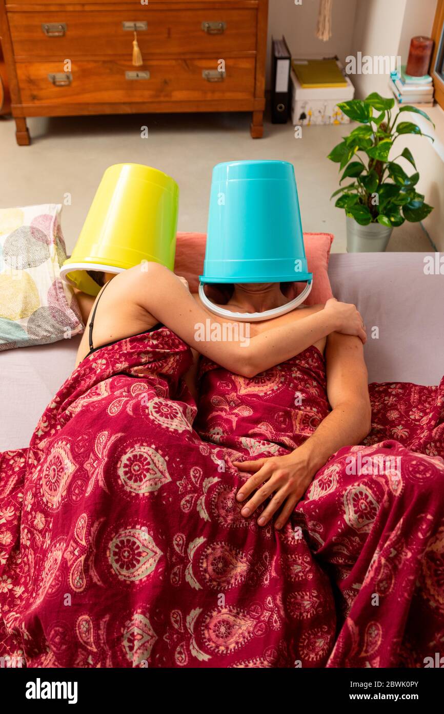 Jeune couple au lit avec un seau sur leur tête, ils font l'amour ou le  repos, mais ils ne parlent pas les uns aux autres Photo Stock - Alamy