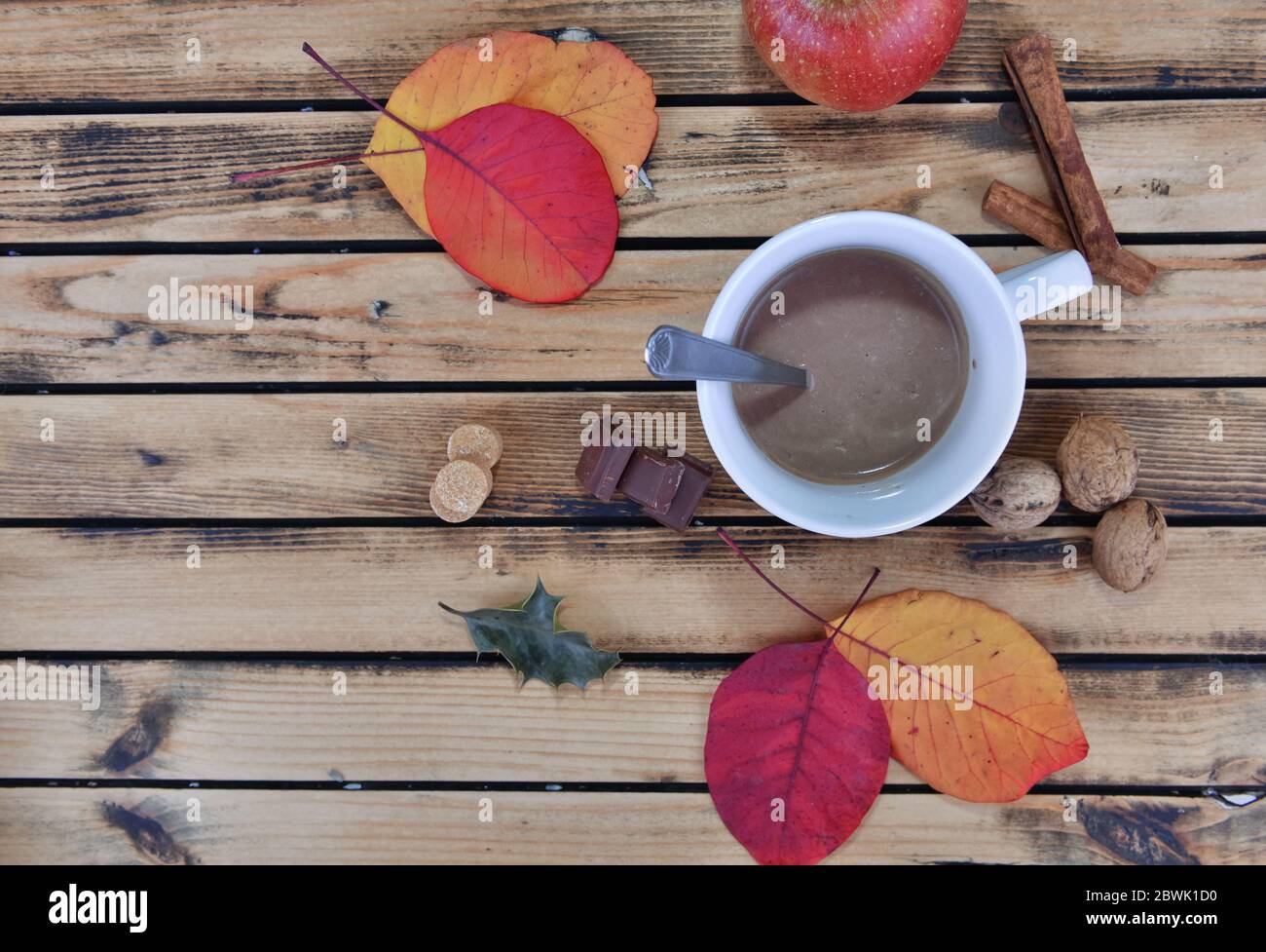 vue de dessus sur le lait au chocolat dans une tasse en automne encore vie avec des feuilles rouges et des épices sur une table en bois Banque D'Images