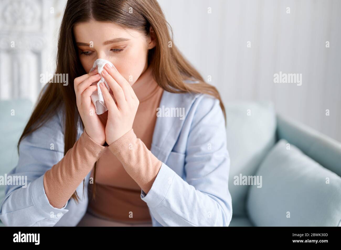 Une fille malade marque dans le mouchoir à la maison, le nez courant, la grippe, le fauche Banque D'Images