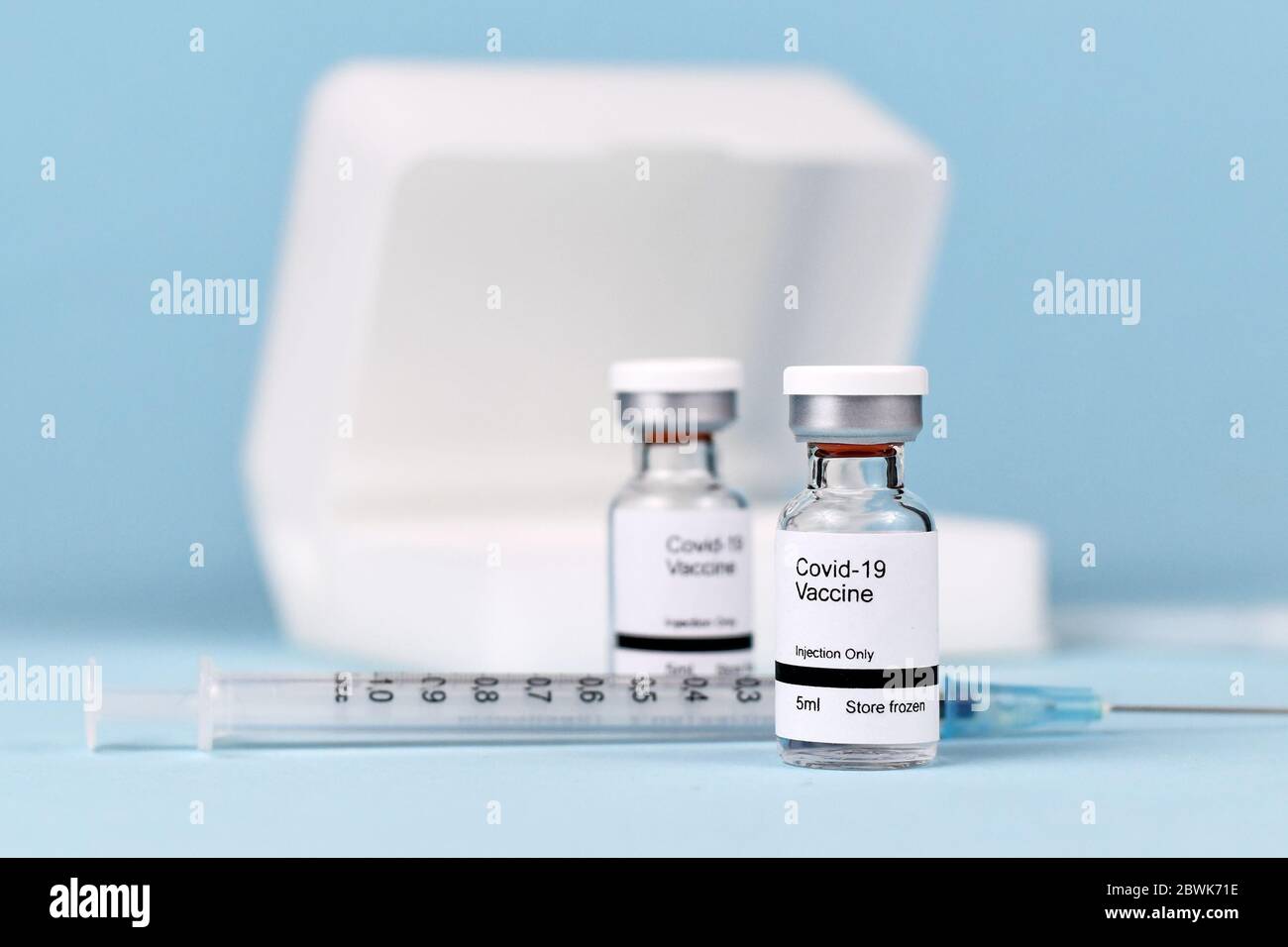 Vaccin contre le coronavirus concept avec deux flacons de petite taille avec le texte « vaccin Covid-19 » avec seringue et étui de stockage sur fond bleu flou Banque D'Images