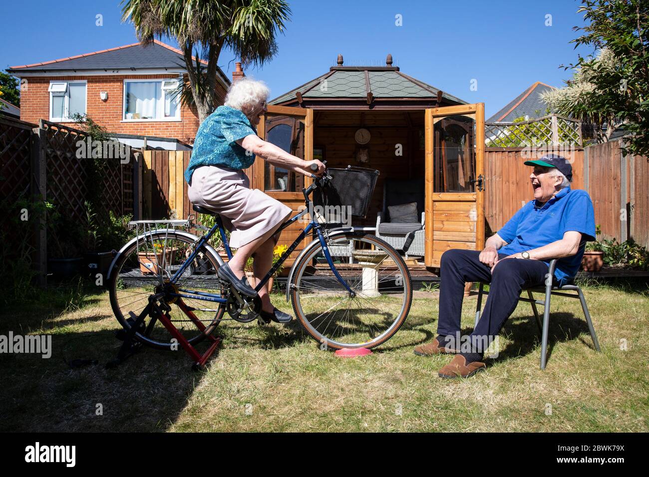 Les deux couples âgés dans leurs années 80 restant en forme sur un pied d'entraîneur de vélo dans leur jardin arrière pendant le verrouillage du coronavirus, sud-ouest de l'Angleterre, Royaume-Uni Banque D'Images